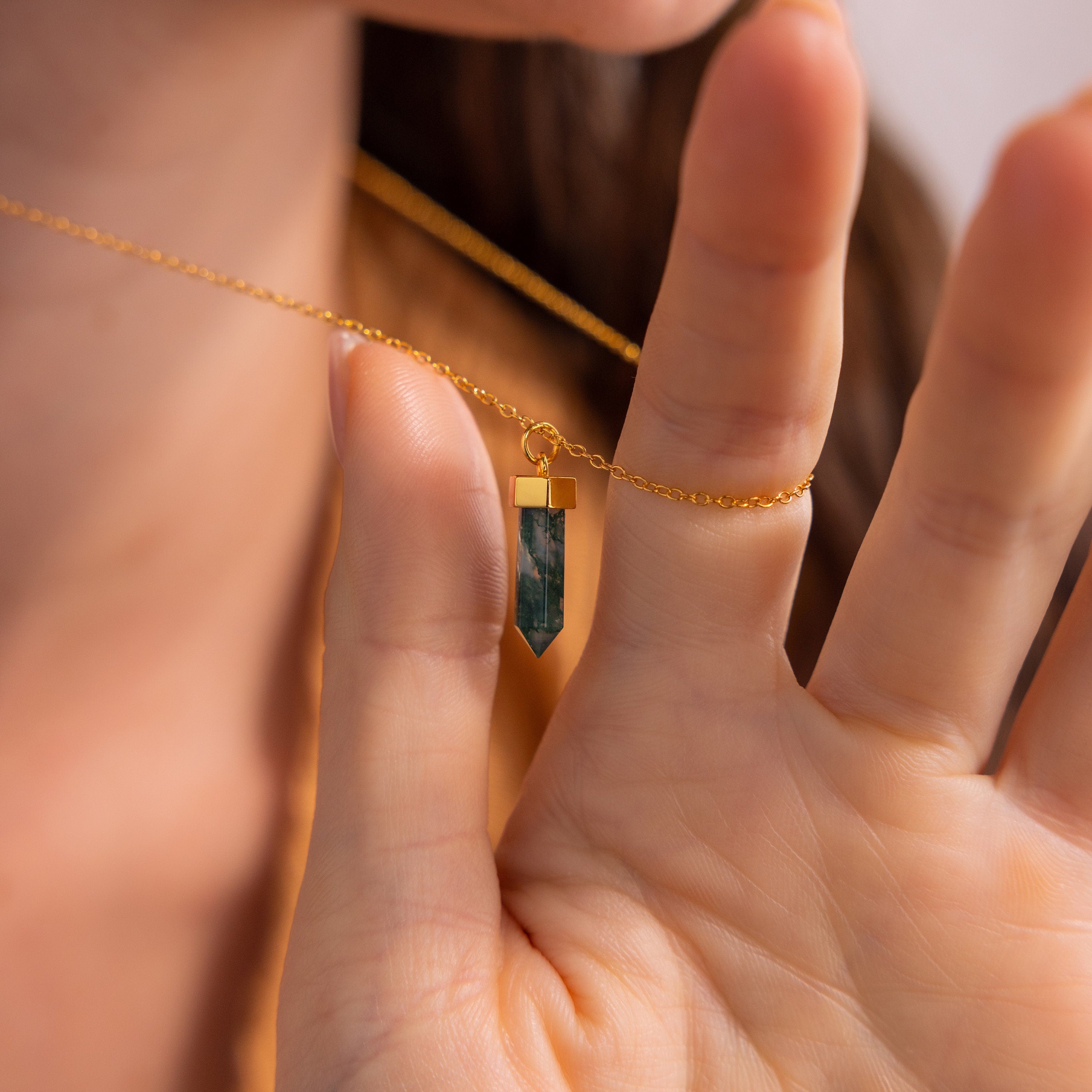 A hand displays the Agate Quartz Necklace near the neck, showcasing its green gemstone charm and marbled design.