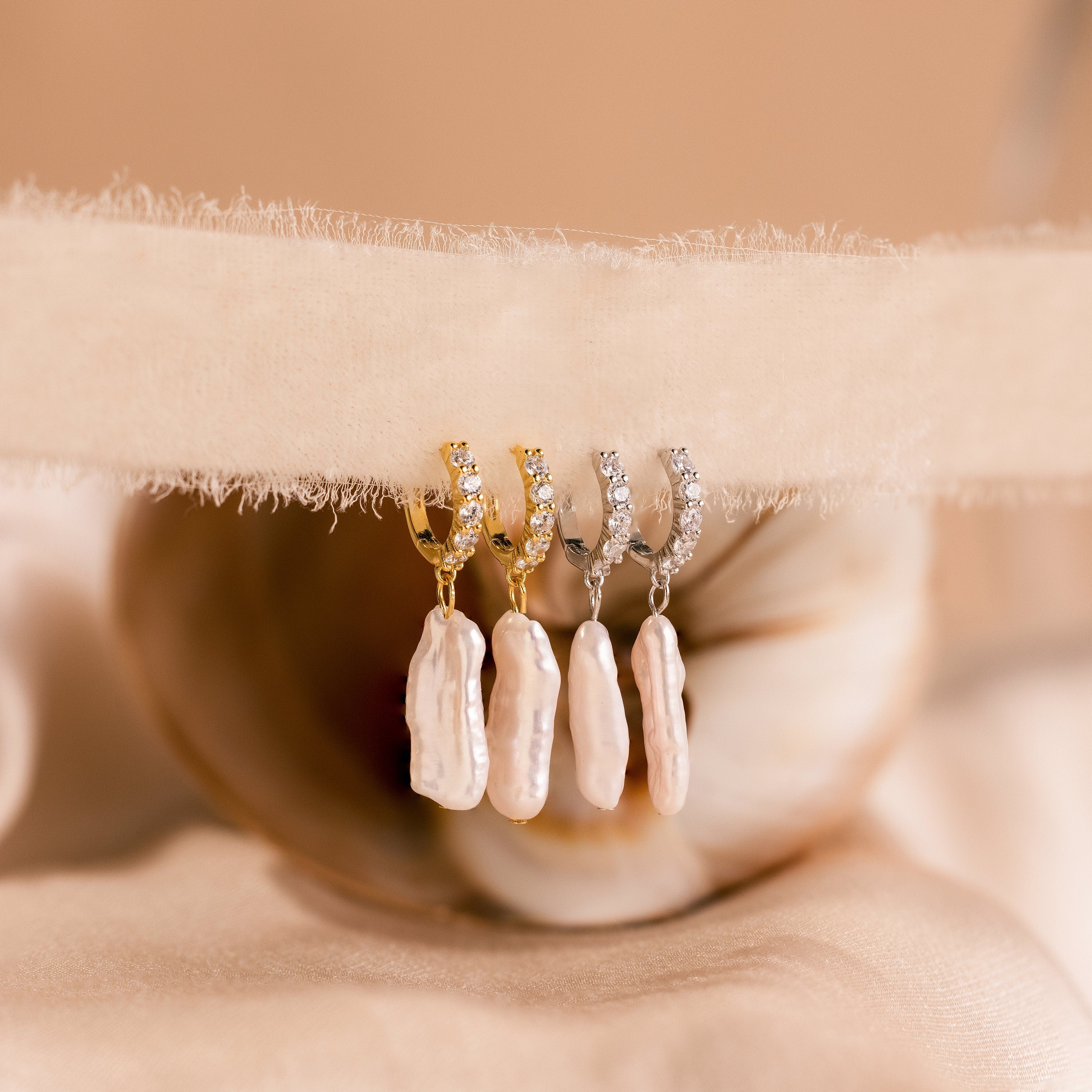 The Baroque Pearl Pave Huggies feature elegant huggie hoops with baroque pearl accents, perfect for adding timeless charm to any jewelry collection.