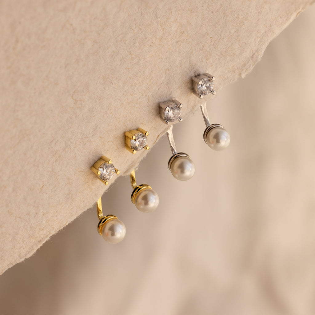 Two pairs of Diamond Pearl Ear Jackets—crafted in gold and silver—showcase sparkling diamonds and pearls, ideal for minimalist jewelry lovers, elegantly displayed on a textured surface.
