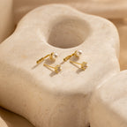 Diamond Pearl Ear Jackets—one featuring a pearl and the other a sparkling diamond—displayed on a textured surface; an ideal choice for minimalist jewelry lovers.