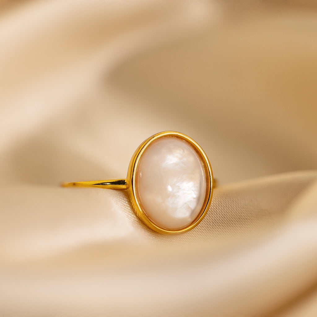 The Mother of Pearl Signet Ring rests on soft beige satin, showcasing vintage-inspired elegance and timeless charm.