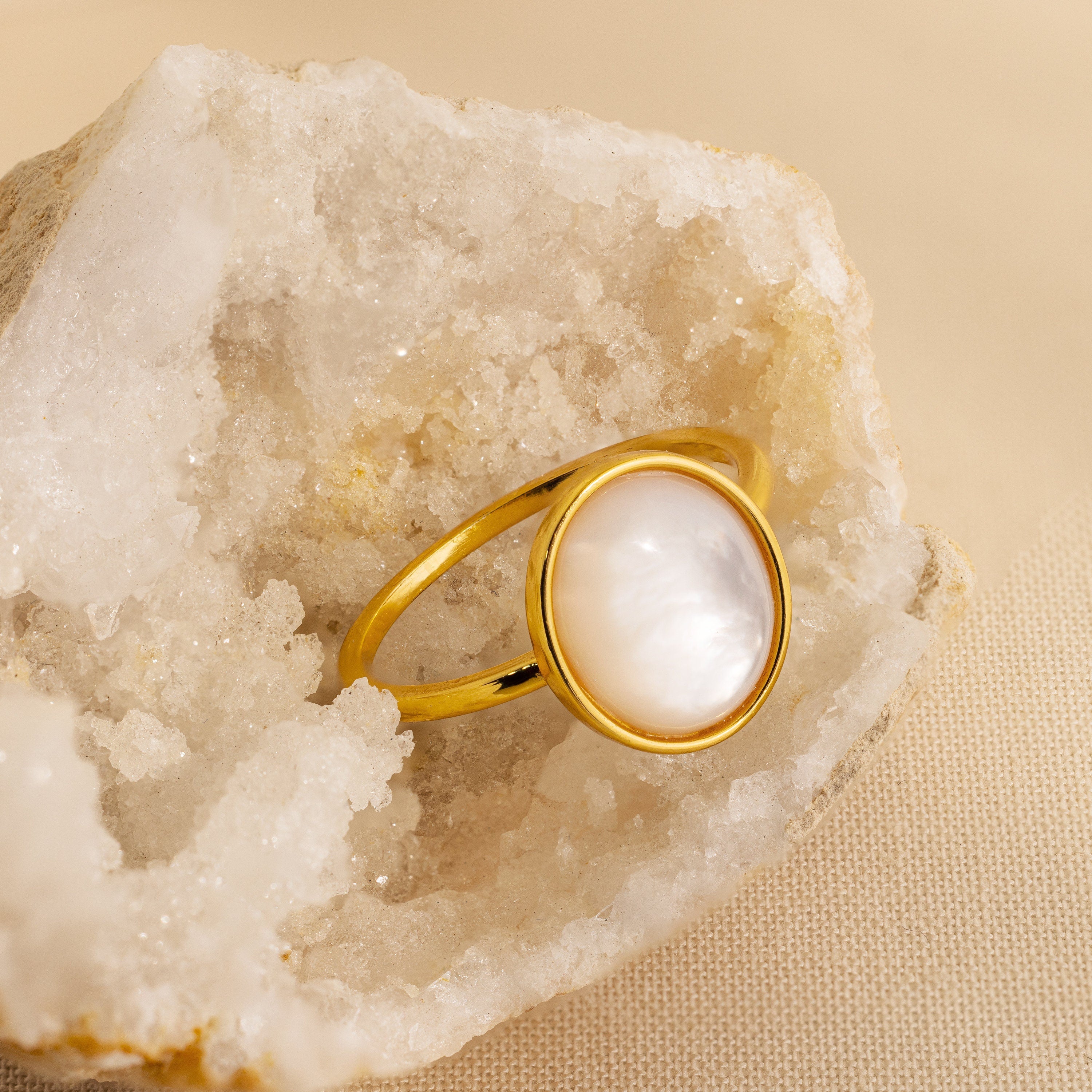 Mother of Pearl Signet Ring in 18K Gold, featuring a round Mother of Pearl stone, showcased on a white crystal rock background.