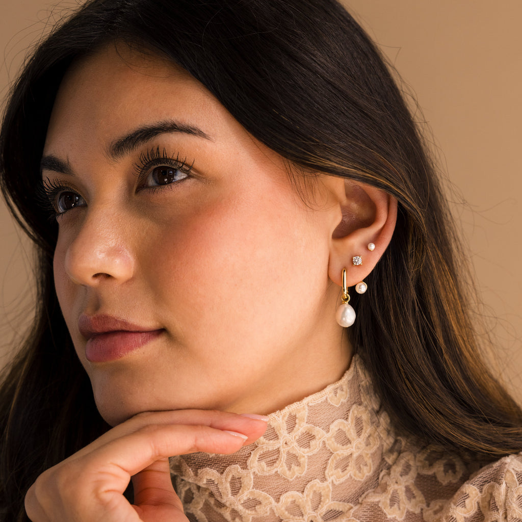 A woman rests her hand under her chin, embodying elegance while displaying the beautiful Freshwater Pearl Drop Hoops.