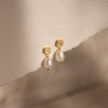 Moonstone Pearl Drop Earrings featuring small white stones and dangling pearls, perfect for any jewelry collection, displayed on textured off-white paper.