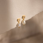 Moonstone Pearl Drop Earrings featuring small white stones and dangling pearls, perfect for any jewelry collection, displayed on textured off-white paper.