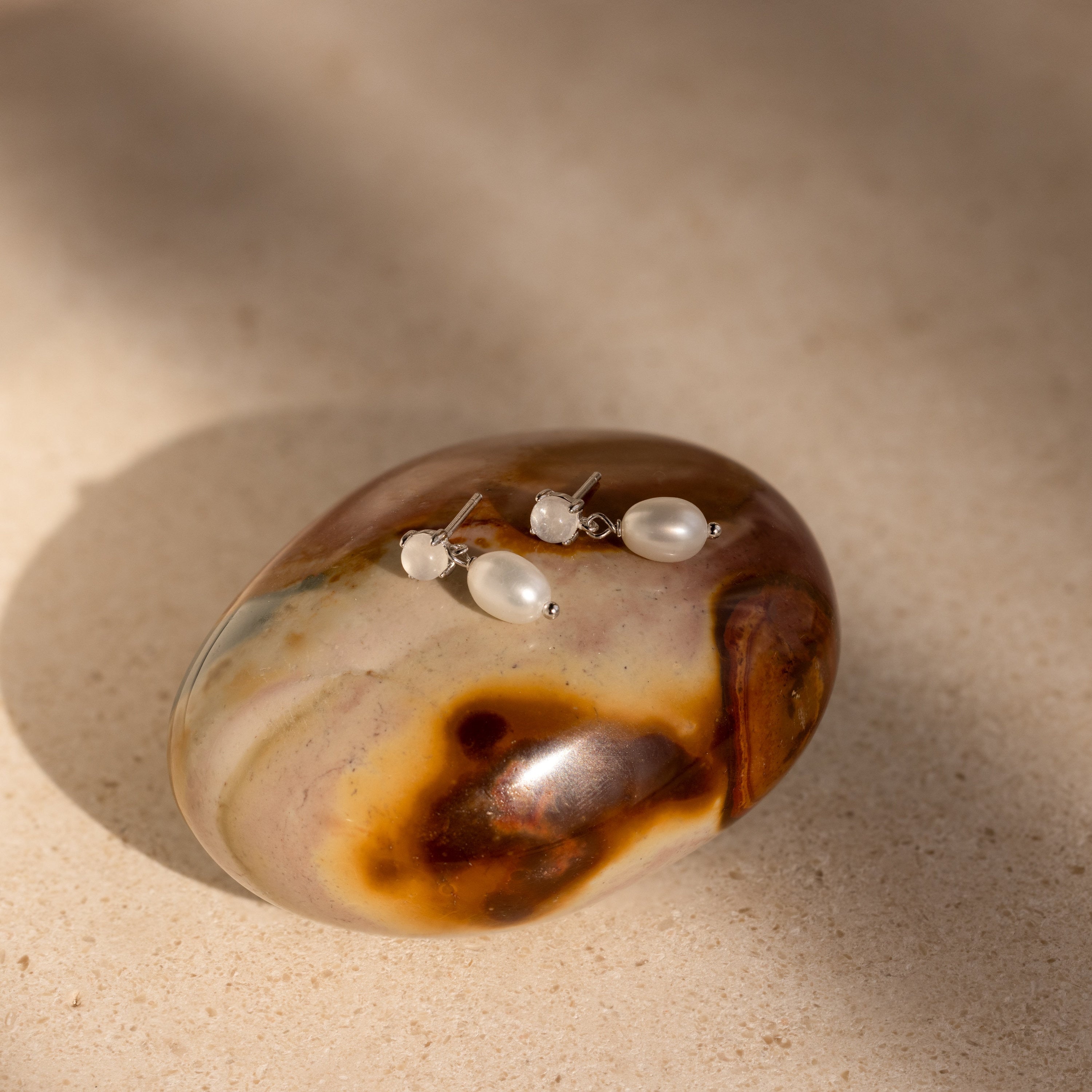 The Moonstone Pearl Drop Earrings are a unique addition to any jewelry collection, featuring elegant pearl drops and shimmering moonstones.