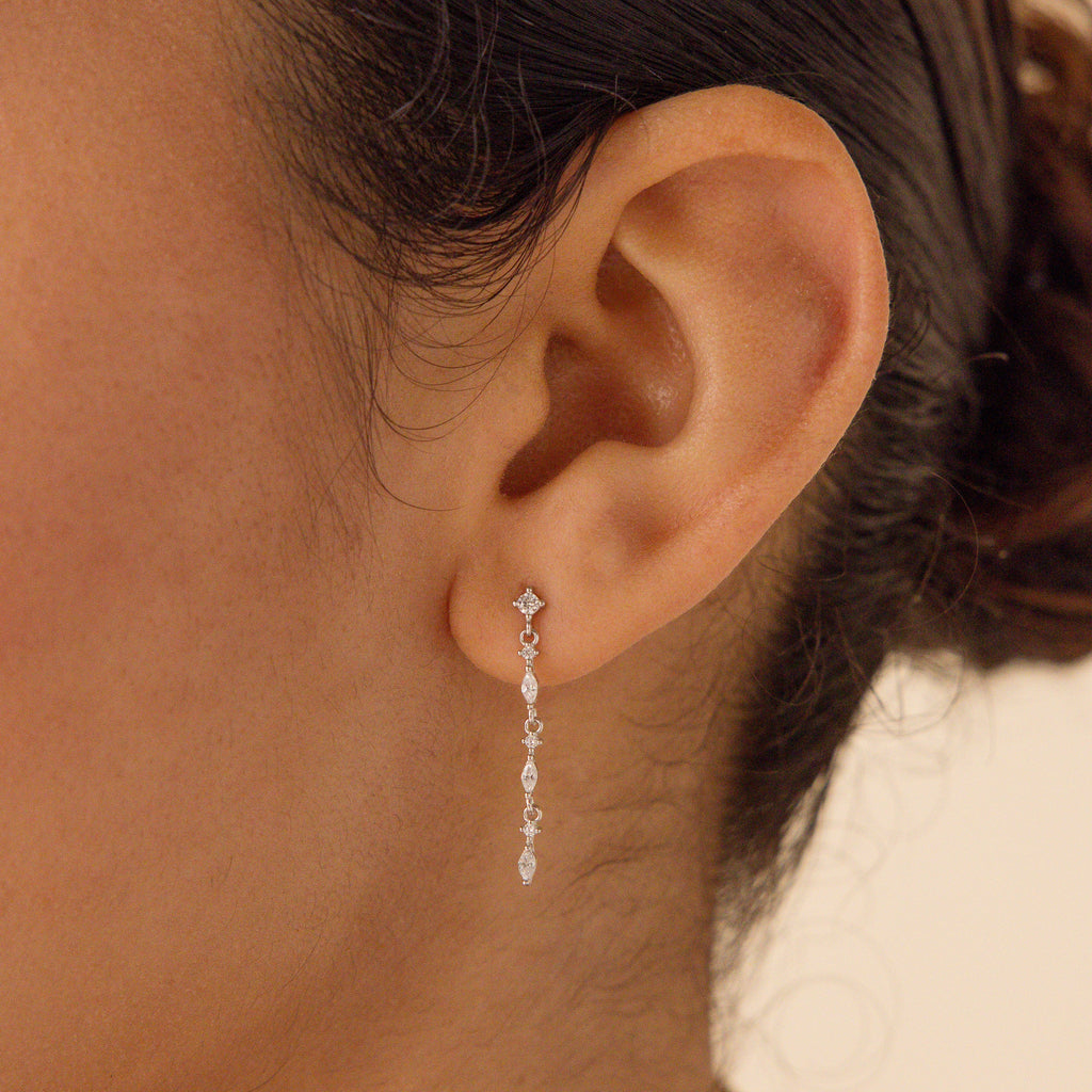 Close-up of a woman's ear wearing Dainty Diamond Drop Earrings—ideal as bridesmaid jewelry or for an elegant wedding look.
