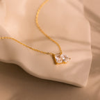Toi et Moi Diamond Necklace featuring an emerald cut diamond pendant sparkling on a soft beige fabric background.