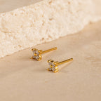 Diamond Ivy Flower Studs with clear gemstones rest on a beige stone surface, offering a versatile accessory ideal for weddings or adding everyday elegance.