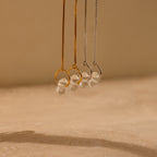 Herkimer Diamond Earrings shine against a neutral beige background, their crystal brilliance reminiscent of elegant pendant necklaces paired with glass stone studs.