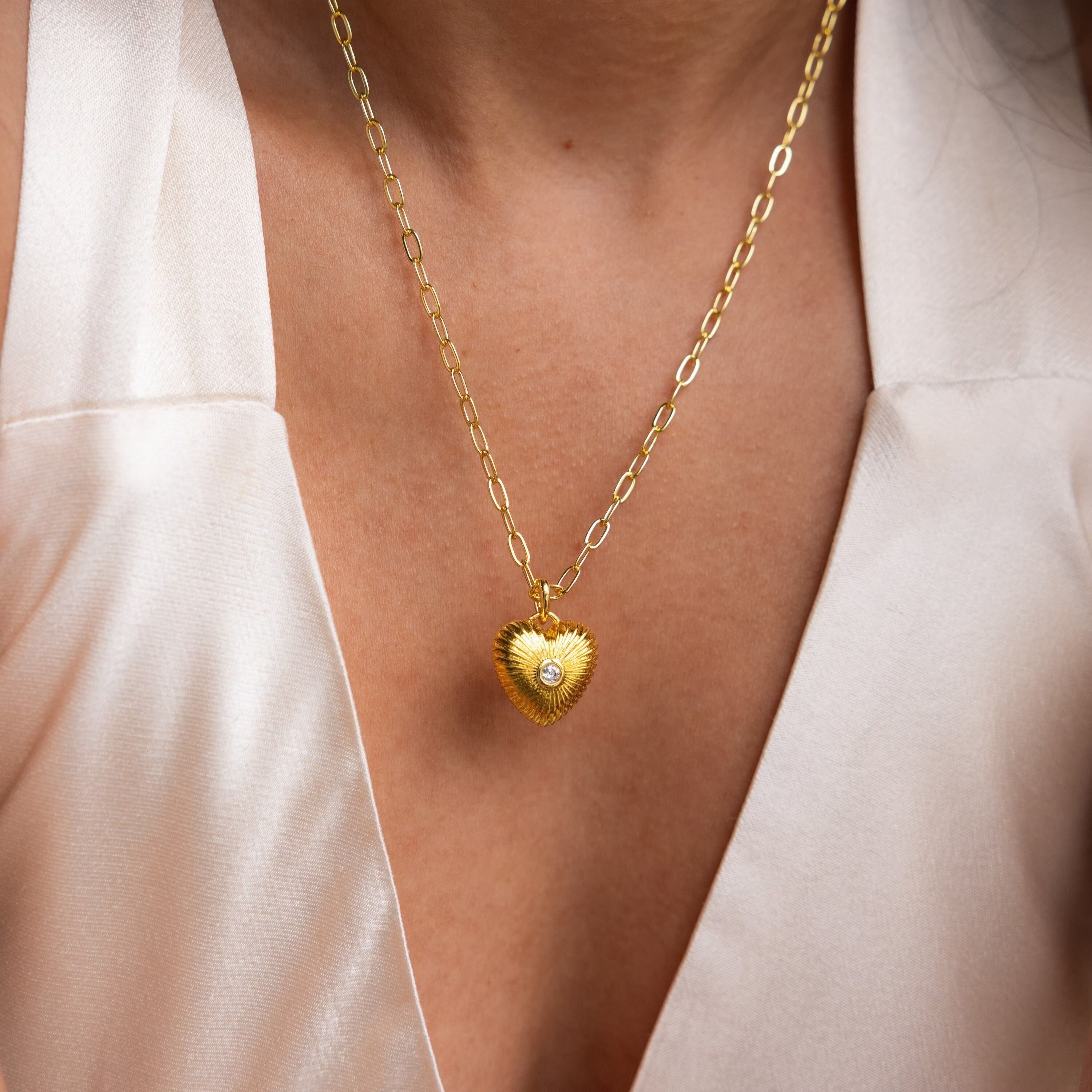 The Diamond Ribbed Heart Necklace, paired with a white v-neck top, adds vintage-inspired charm and elegance to your look.