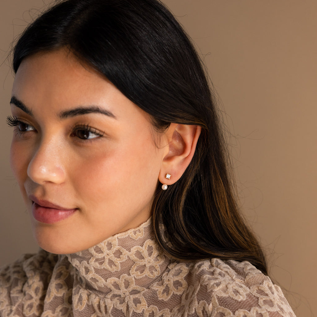 A woman with long dark hair, wearing Diamond Pearl Ear Jackets and a lace turtleneck, gazes to the side against a neutral background.