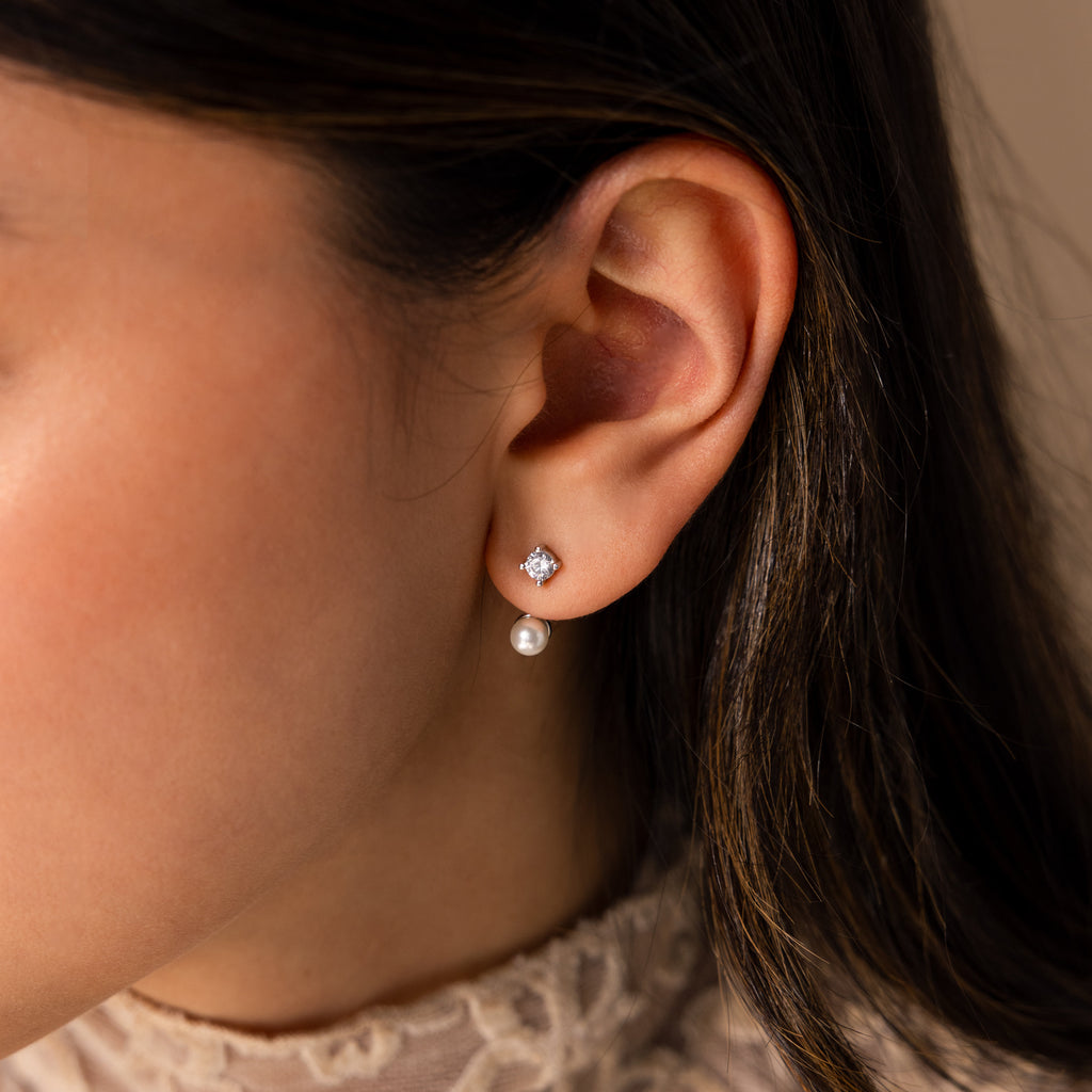 Close-up of a woman’s ear wearing Diamond Pearl Ear Jackets—minimalist earrings featuring a pearl drop with a sparkling diamond accent above it.