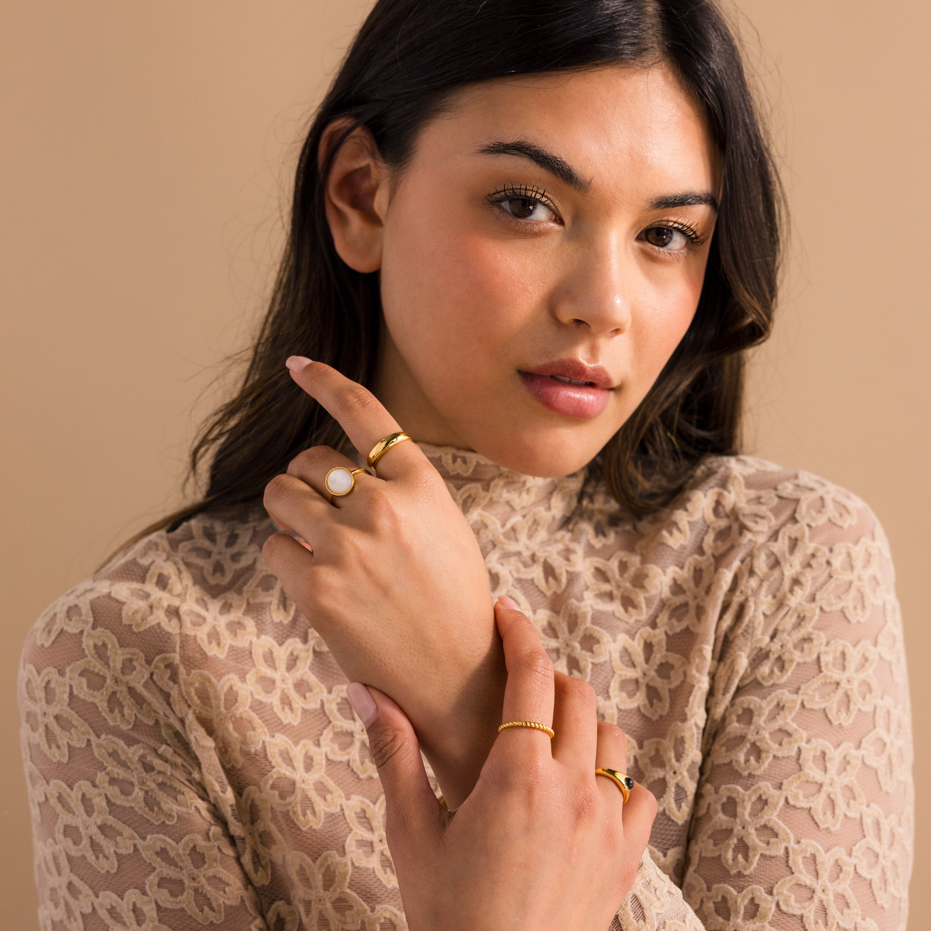 Woman in a lace top poses with her hands crossed, showcasing the Mother of Pearl Signet Ring against a beige background.