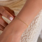 Wearing the Heart Link Chain Bracelet, a person gently touches their wrist, showcasing the romantic elegance of this delicate jewelry.
