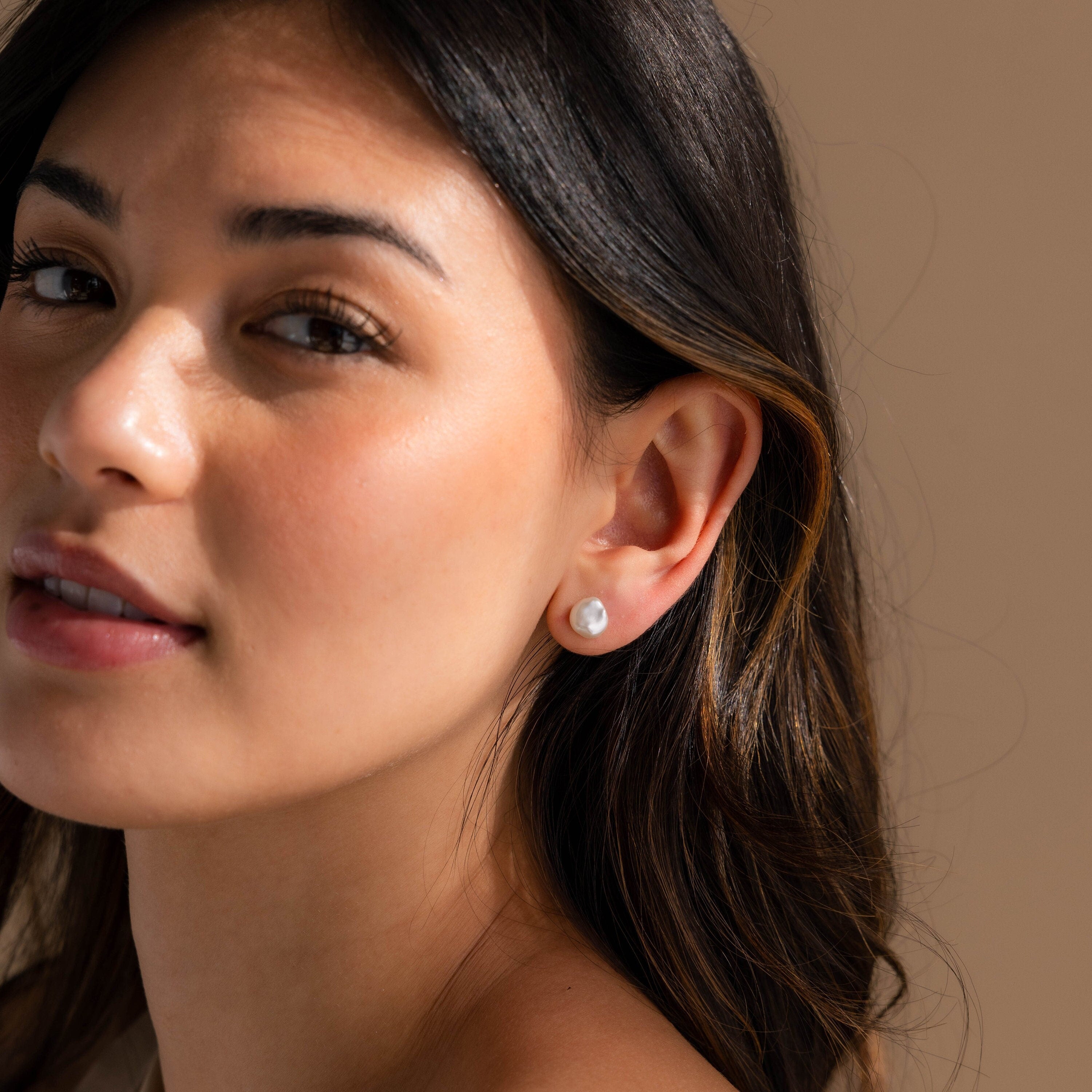 A woman with long hair exudes timeless elegance, highlighted by her exquisite Freshwater Pearl Studs.