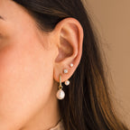 Close-up of an ear with four piercings adorned with elegant jewelry, including Freshwater Pearl Drop Hoops alongside gold hoops and diamond studs.