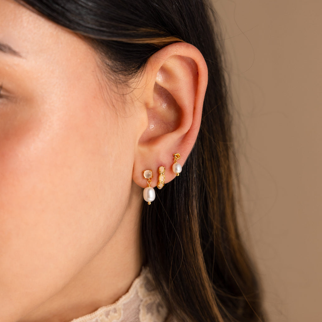 Close-up of a woman's ear adorned with Moonstone Pearl Drop Earrings against a neutral background—these earrings are a stunning addition to any jewelry collection.