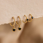 Elegant Pave Onyx Drop Huggies: gold hoops adorned with black onyx gems and sparkling clear stones, plus a small pair featuring bold black stones.