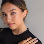 A woman posing for a photo, highlighting the Onyx Beaded Huggies adorned with a bold hexagonal Onyx charm.