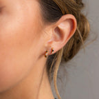 A close-up of a woman’s ear adorned with chic Tiny Onyx Pearl Bar Studs.