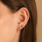 Close-up of a woman's ear featuring two green gemstone earrings—a stud and a hoop—highlighting nature-inspired jewelry with Emerald Ivy Flower Studs.