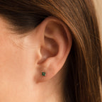 Close-up of a woman's ear wearing the Emerald Ivy Flower Studs, featuring an elegant square green gemstone in a nature-inspired design.