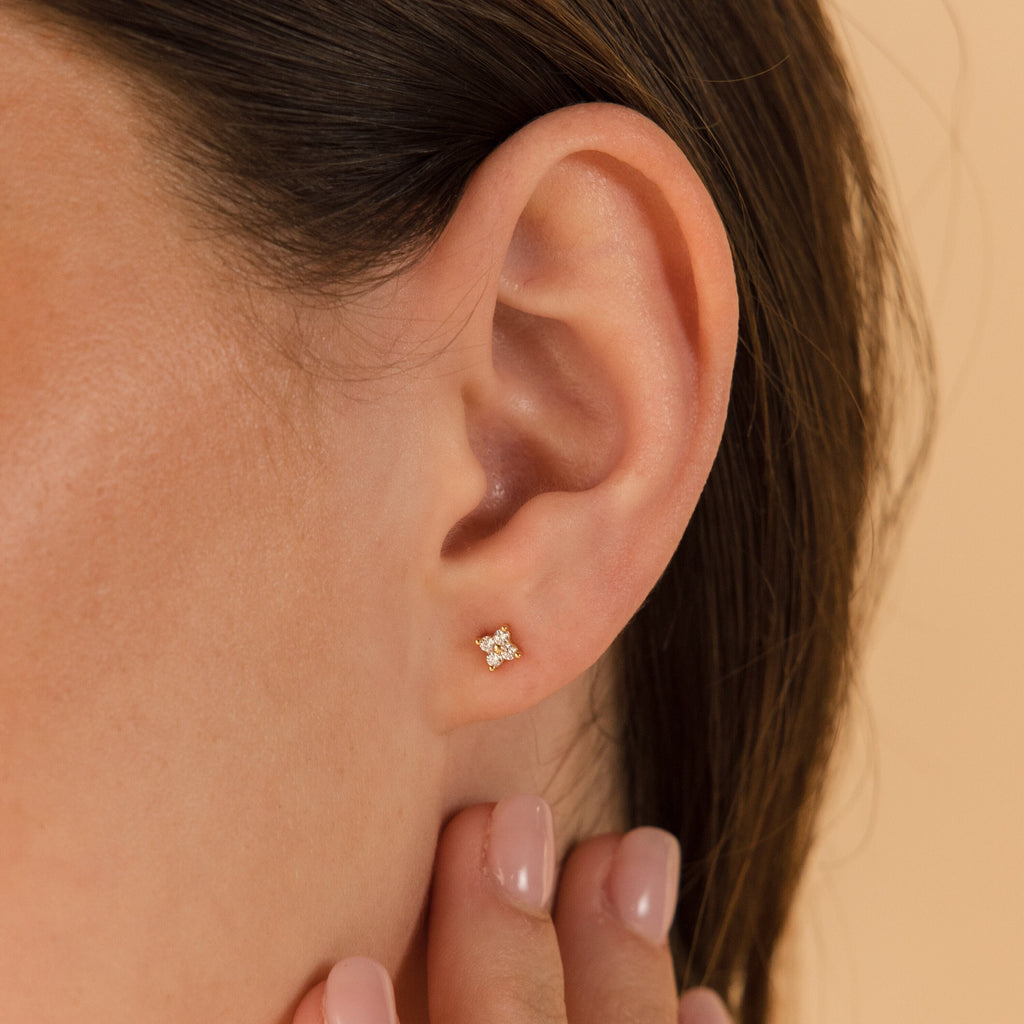 Close-up of a woman's ear adorned with Diamond Ivy Flower Studs, an elegant and versatile accessory ideal for weddings; her hand is near her ear.