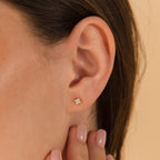 Close-up of a woman's ear adorned with Diamond Ivy Flower Studs, an elegant and versatile accessory ideal for weddings; her hand is near her ear.