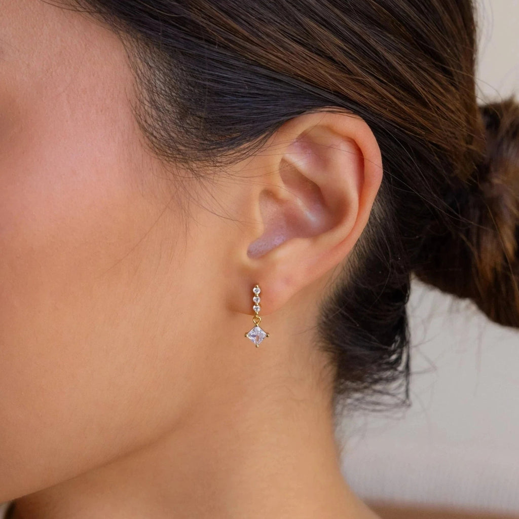 A close-up of a woman's ear adorned with the elegant Princess Diamond Drop Studs.