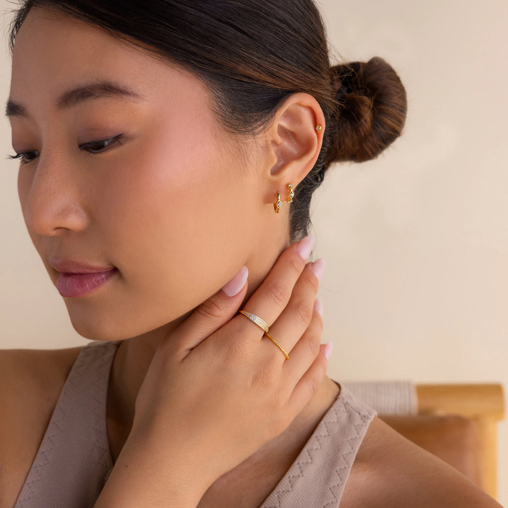 A woman with a ring on her hand wears elegant Ericka Diamond Hoops, adding a touch of sophistication to her look.