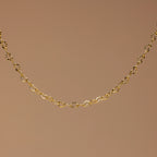 The Heart Link Chain Bracelet features small, repeating heart-shaped links for a romantic look, elegantly displayed against a plain brown background.