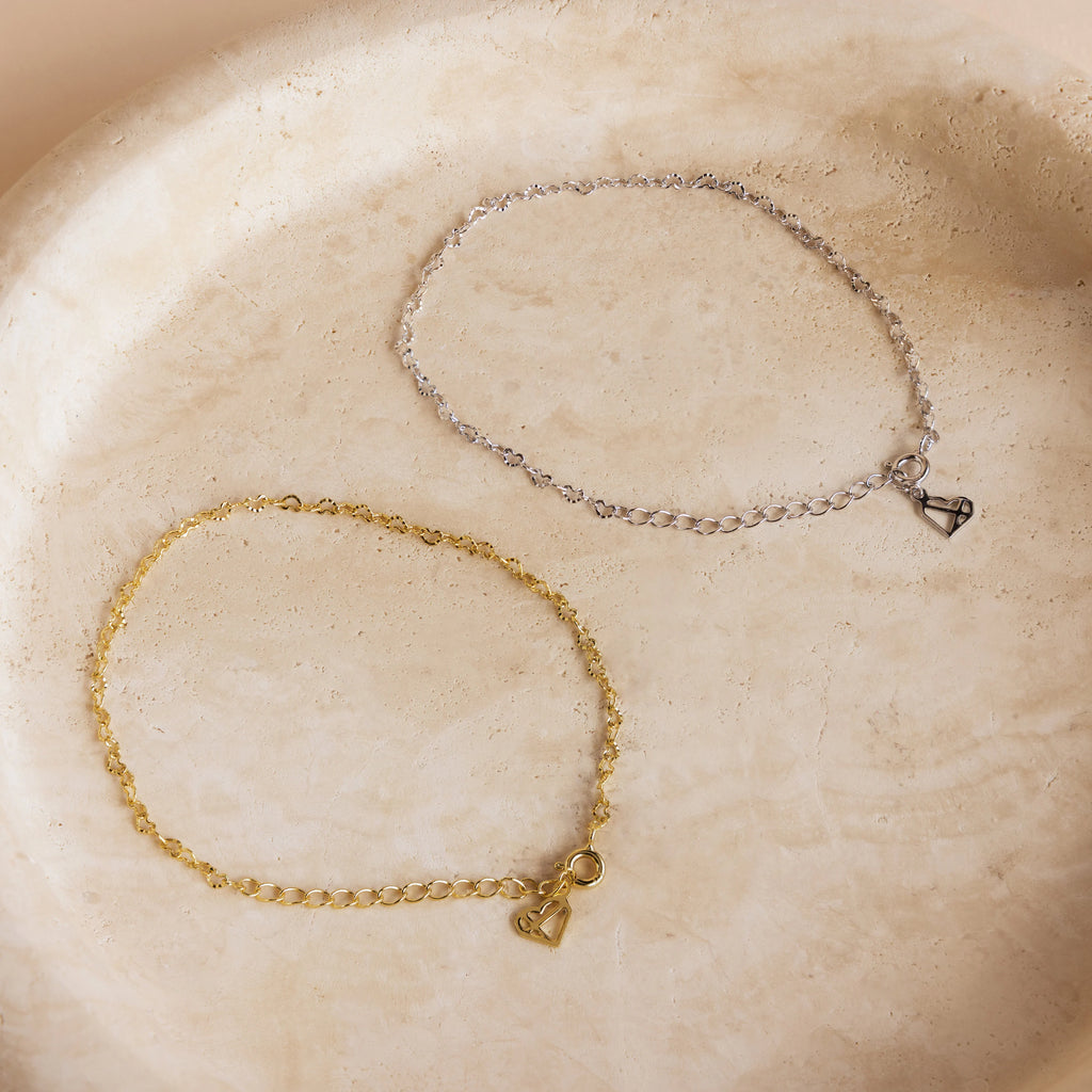 Heart Link Chain Bracelet in gold and silver, featuring small heart charms, perfect for coquette style, displayed on a light stone surface.