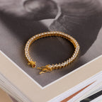 The 3 Prong Tennis Bracelet with clear gemstones rests atop a stack of books, making an elegant statement piece.