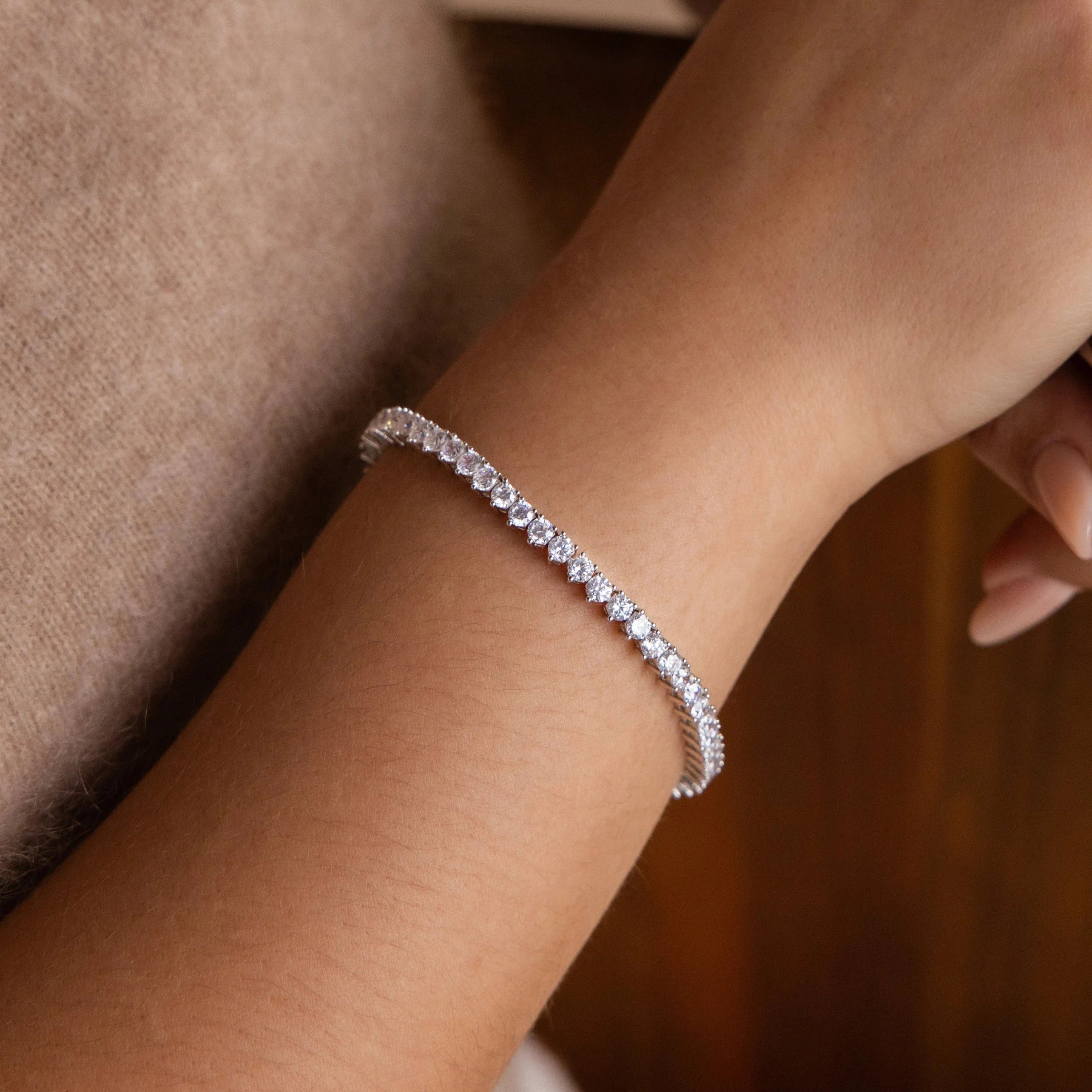 A close-up of a wrist wearing the 3 Prong Tennis Bracelet—a delicate, sparkling accessory that exudes timeless elegance.