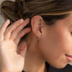 A close-up of a woman's ear wearing Onyx Baguette Drop Huggies.
