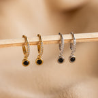 A stick displays a row of elegant Pavé hoops, featuring the Pave Onyx Drop Huggies.