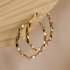 Large Twisted Hoops displayed on a beige ribbed background—these textured earrings are a stylish accessory for summer.