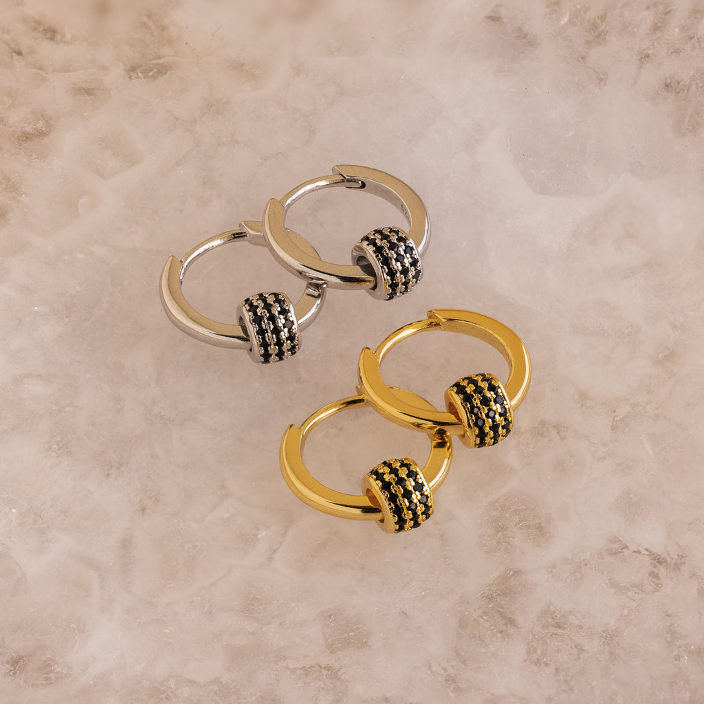 A set of Onyx Pave Beaded Hoops displayed on a marble surface.