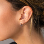 Close-up of a woman with blonde hair pulled back, wearing elegant Pearl & Onyx Huggies.