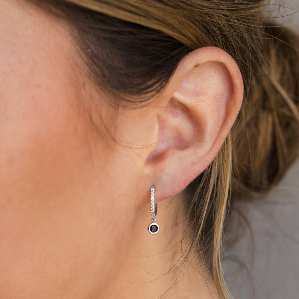 A close-up of a woman's ear showcases the refined sparkle and timeless style of the Pave Onyx Drop Huggies.