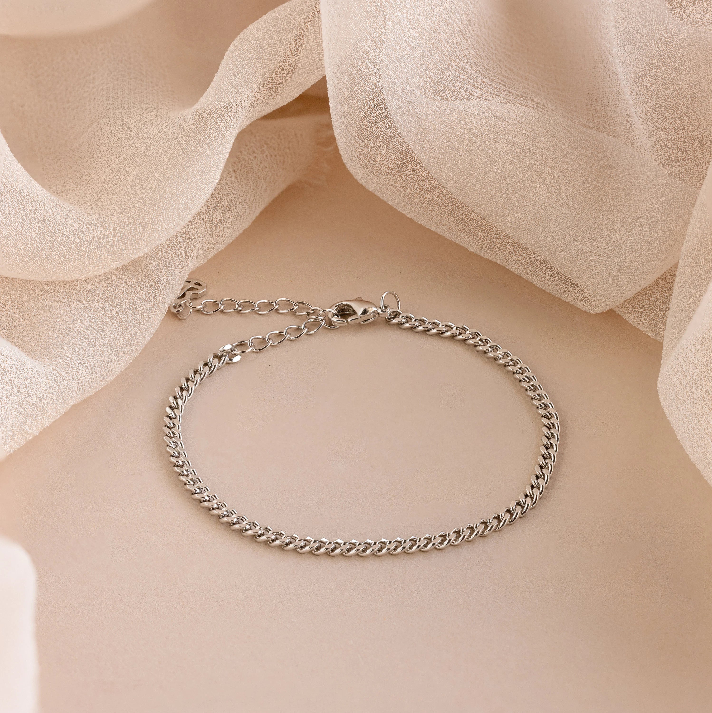 A minimal jewelry essential, the Curb Chain Bracelet is elegantly displayed on a soft beige fabric—perfect for effortless layering.