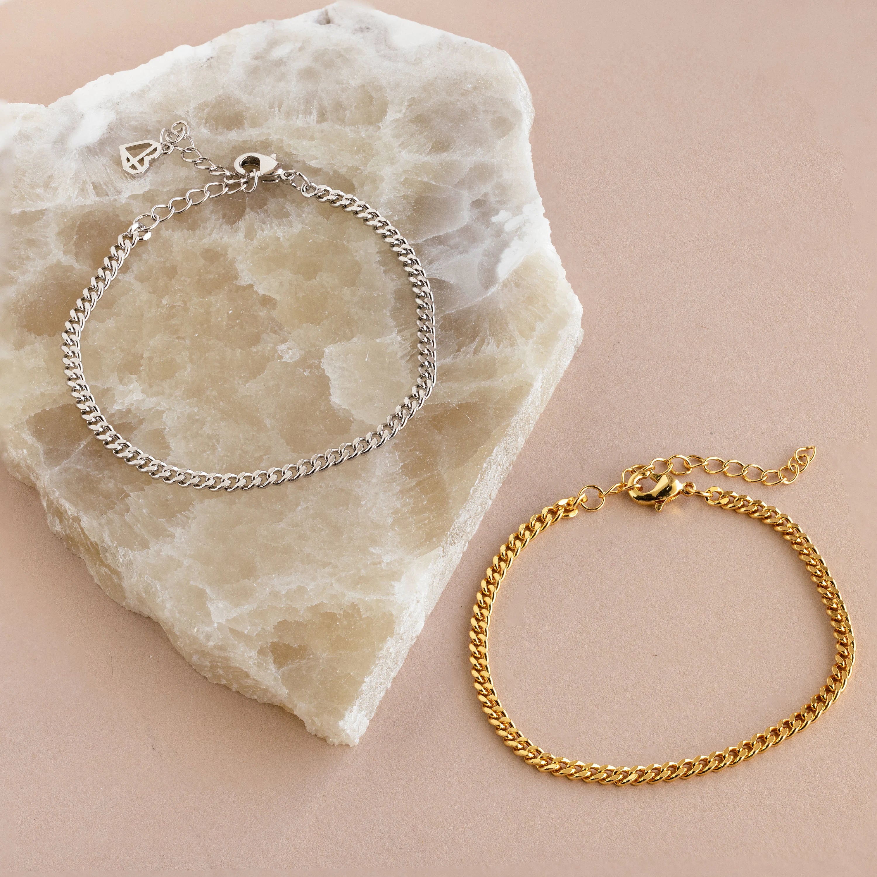 Minimal jewelry shines in the Curb Chain Bracelet, elegantly presented on a light marble slab and beige surface for a chic, layered style.