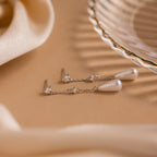 The Diamond Pearl Chain Earrings lie elegantly on the table, showcasing sparkling diamond studs and a graceful teardrop pearl charm.