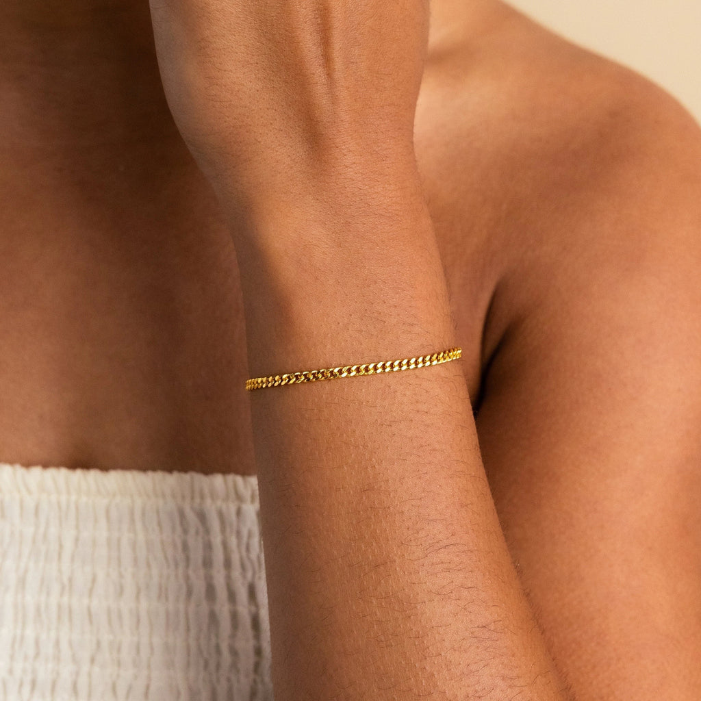 A person wears the Curb Chain Bracelet on their wrist, paired with a white textured top for a minimal jewelry style and easy layered look.