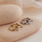 The Pear Diamond Drop Hoops—available in gold and silver, each set with a teardrop-shaped stone—rest on textured stones, perfect as a wedding accessory or a chic addition to your elegant earring collection.