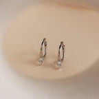 Elegant and timeless, the Pear Diamond Drop Hoops showcase teardrop-shaped crystals on classic silver hoops against a beige background—an ideal wedding accessory.