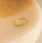 Diamond Station Ring featuring small diamonds displayed on a smooth, beige marble surface.