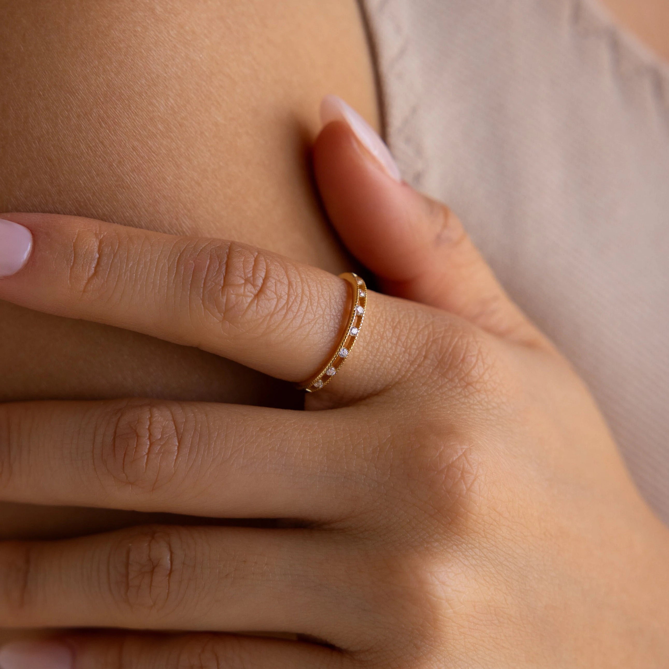 A hand adorned with the Diamond Station Ring, accented by delicate diamonds, rests gently on a person's chest.