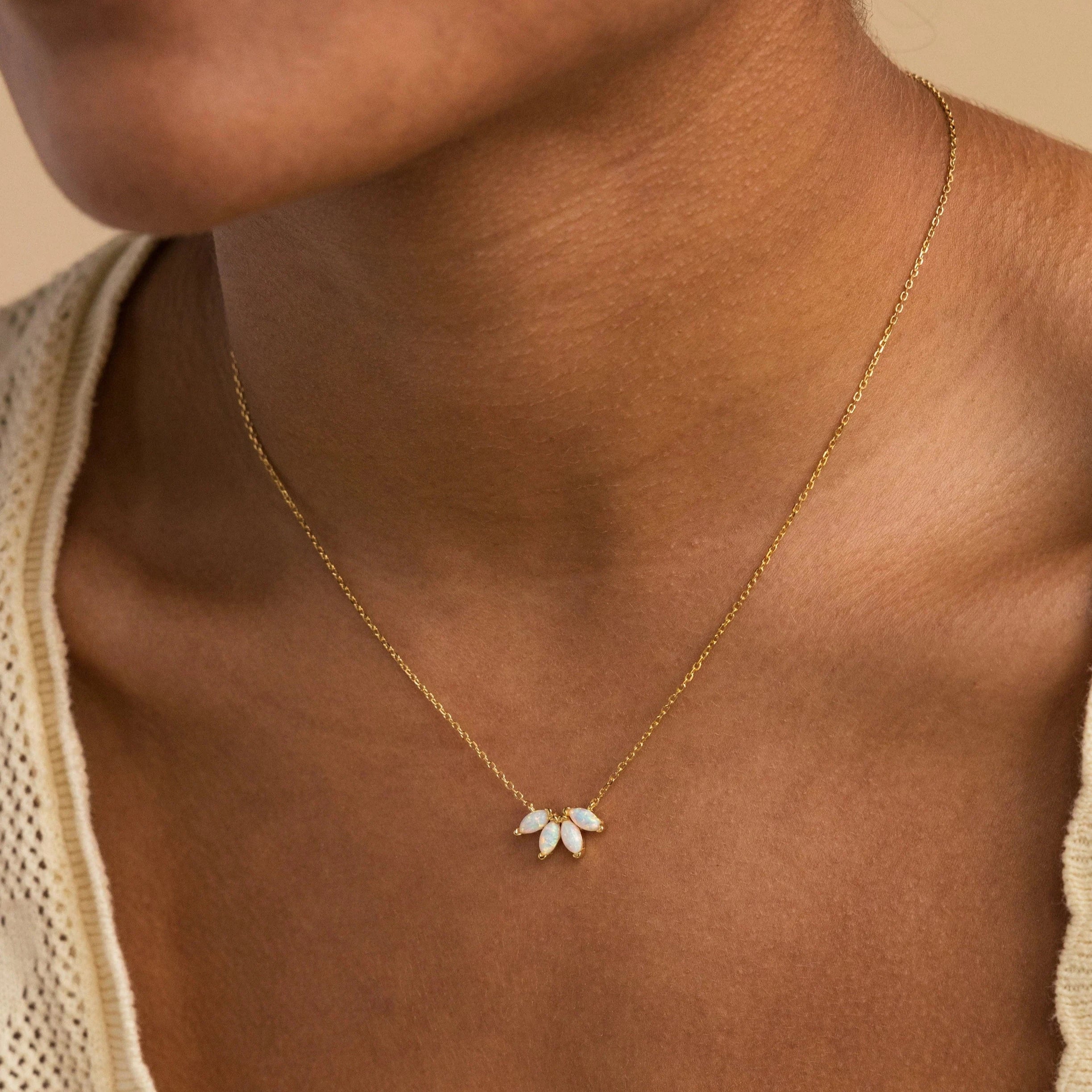 The White Opal Marquise Necklace, featuring gold floral design with white stones, adds a touch of timeless charm when elegantly worn on a woman's neck.